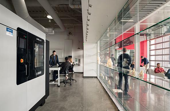 Lockheed Martin Lab with students working at a table and a large 3D printer